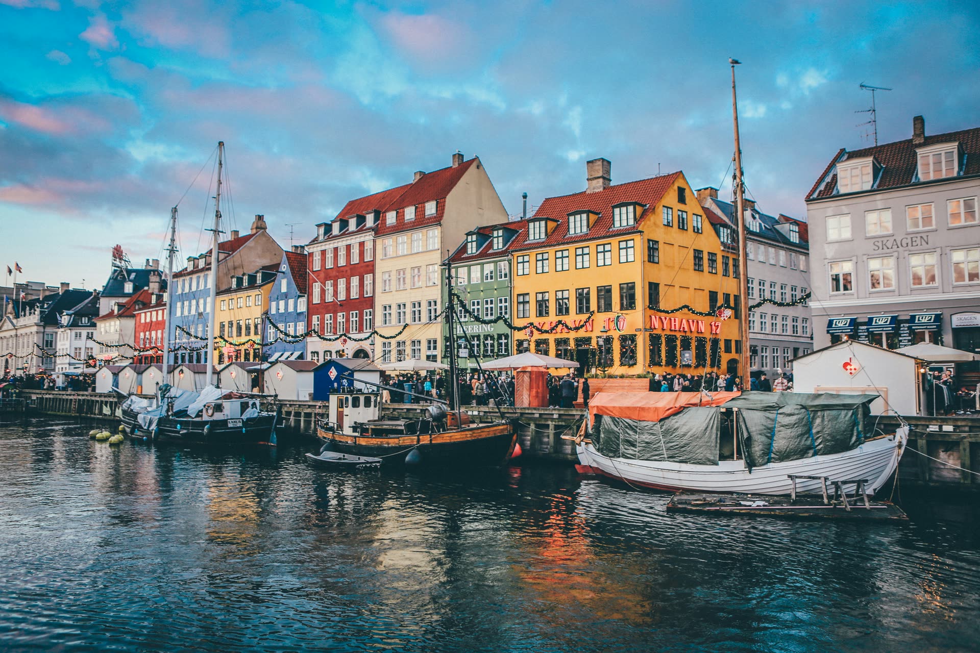 Colorful canal-front houses and moored boats in Copenhagen's Nyhavn district at dusk
