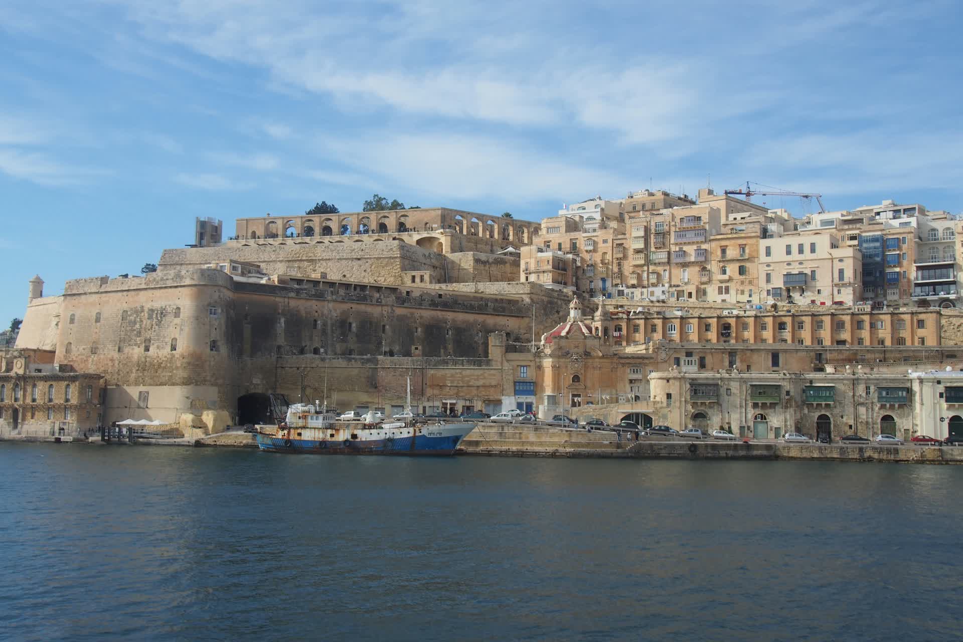 Valletta's fortification walls and honey-colored limestone skyline seen across the Grand Harbour