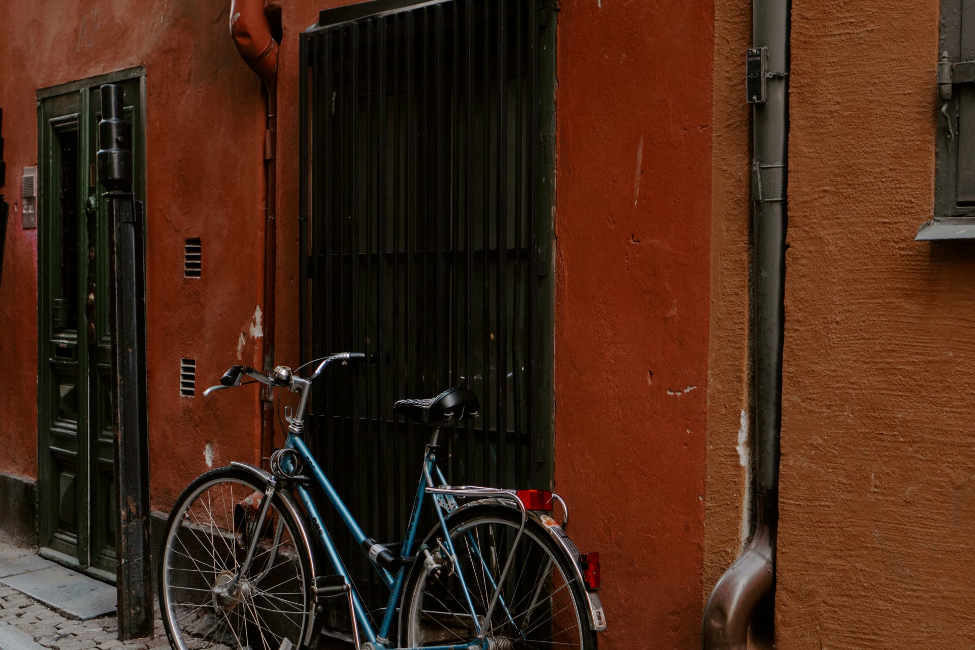 A bicycle parked against a red building on a cobblestone street in Stockholm's Gamla Stan